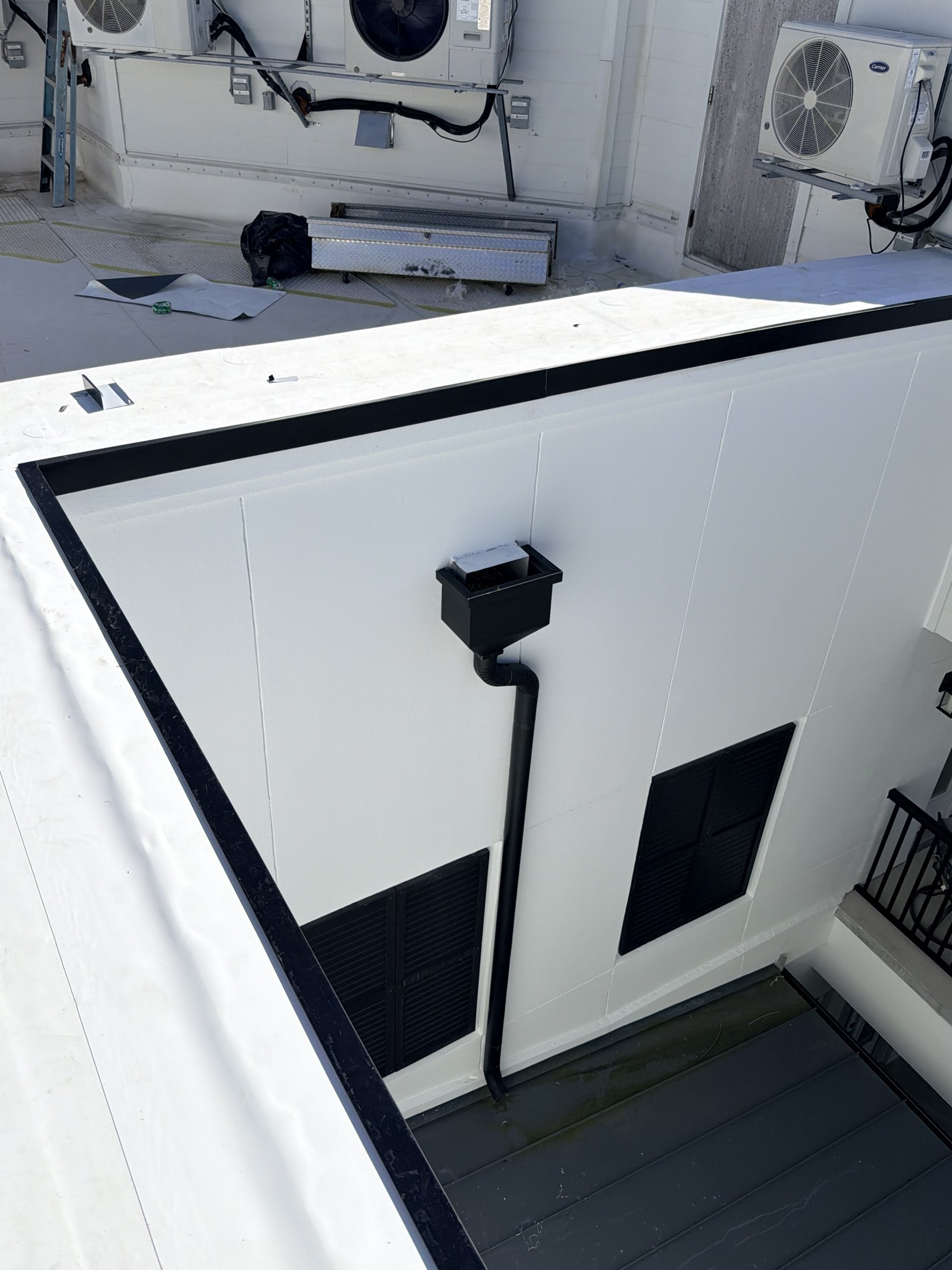 White TPO parapet and black metal edge trim surrounding a lower roof area at the Miramar Beach property